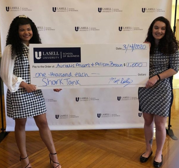 Two student winners holding an oversized check