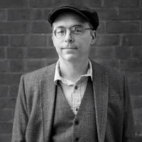 a white male writer with glasses and an Irish cap in a suit 