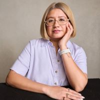 a Salvadoran woman with a bob haircut and glasses resting a hand on her face