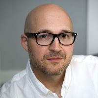 a smiling white man with glasses, low-cut beard, and shaved head