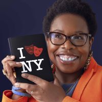 a smiling Black woman with glasses holding a booklet that says I Love N-Y