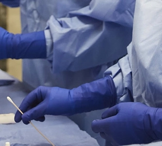 hands in operating room holding a cotton swab