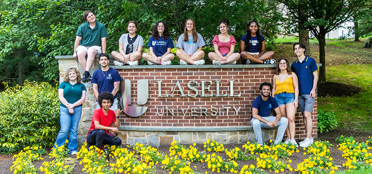 Orientation leaders around Lasell brick sign