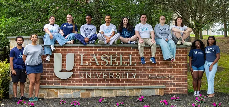 Orientation leaders around Lasell brick sign