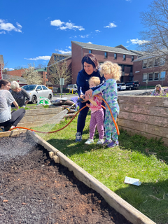 Lasell faculty member Cris Haverty, with students from The Barn, watering the community garden