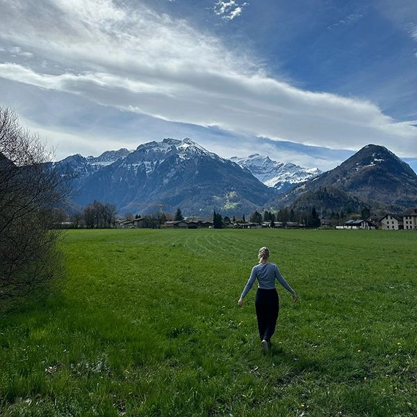 student in a field with mountains in background on study abroad trip